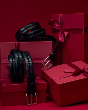 Black belts and red gift boxes on a solid background