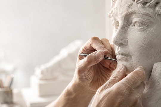 Artistry in Motion: A sculptor's hands meticulously shape a classical bust, revealing the delicate process of artistic creation and the pursuit of timeless beauty.