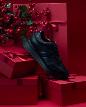 Black sneaker on red gift boxes with green leaves