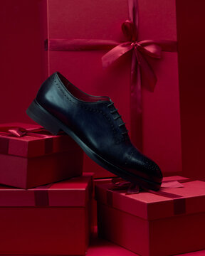 Shoe displayed with red gift boxes in background