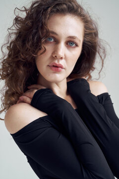 Woman with Blue Eyes Posing with Hands Behind Neck in Minimal Studio 