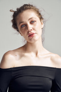 Woman poses indoors with casual expression and simple top