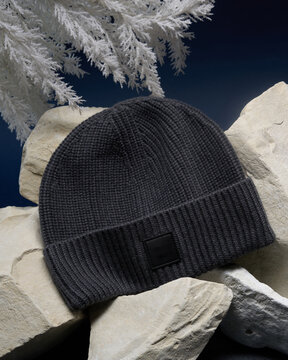 Warm knit hat rests on stones in winter setting