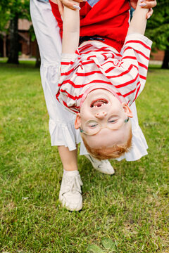 A child hangs upside down holding his mother's hands