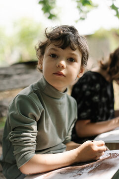 Inspired curly haired boy creating outdoor artwork