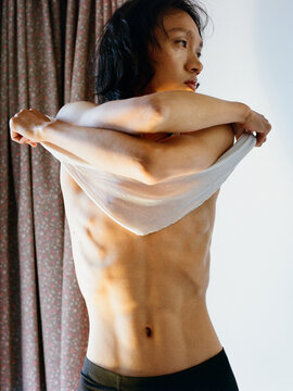 Young Person Removing Shirt in Warm Indoor Light