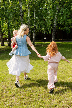 Children and mother play in a green park area.