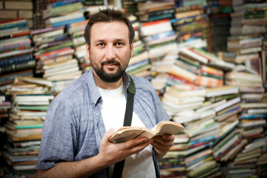 Man Reading Among Book Stacks