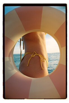 A woman in a yellow bikini framed by a striped swim ring