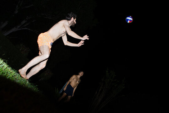 People Playing Volleyball at Night in a Backyard