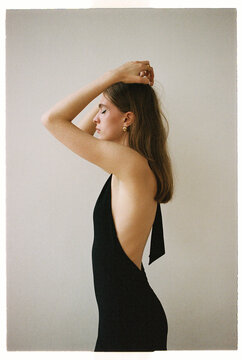 Model poses in a black dress with open back