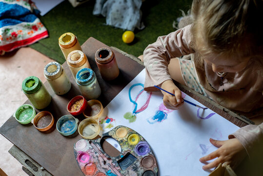 Little child painting in the children's playhouse in the garden