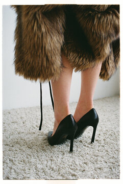 Fashionable woman wears black high heels and a fur coat