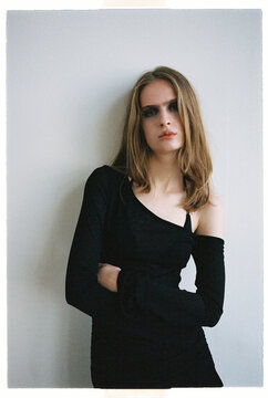 Model stands against a plain wall while wearing a black outfit
