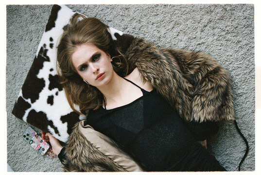 Fashion Model lies on a couch with a cow print pillow