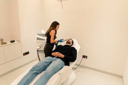 Derm examines male patient skin at follow-up in specialized clinic.