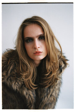 Model poses for a fashion shoot wearing a fur coat in a studio