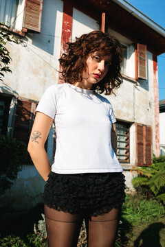 Serious woman posing outside house