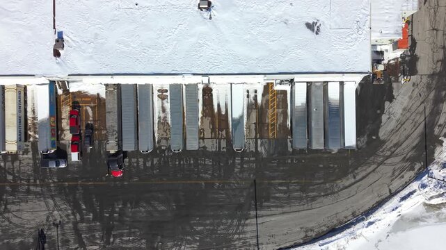 Birds eye view of a modern logistics distribution center with trucks at the loading dock during a crisp winter day