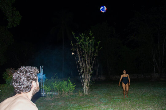 People Playing Volleyball at Night in a Backyard
