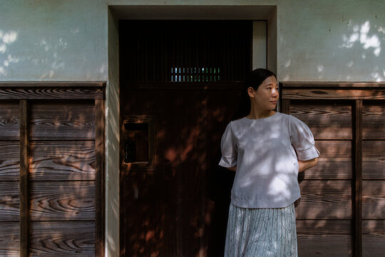 A Woman Taking a Break in Front of a Quaint Wooden Door in a Garden.