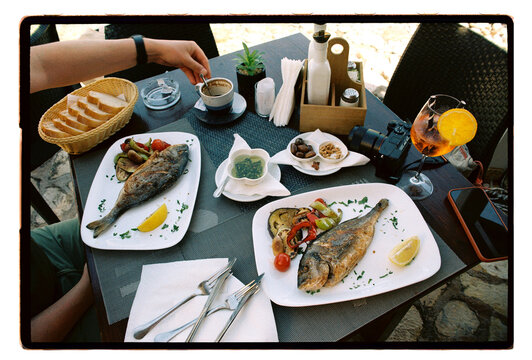 Two whole grilled fish served at an outdoor seaside restaurant