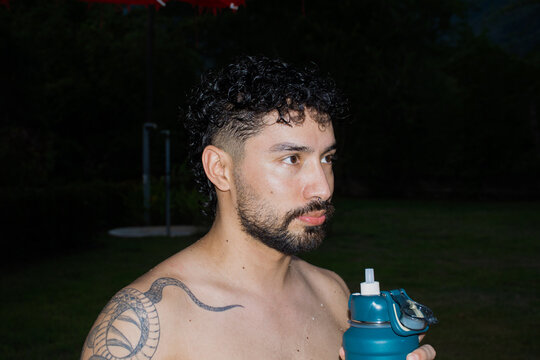 Man Holding Water Bottle Stands Outside in Evening Light