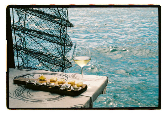 Oysters and white wine at a waterside table beside crab pots