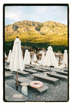Empty beach club loungers beneath a dramatic mountain backdrop