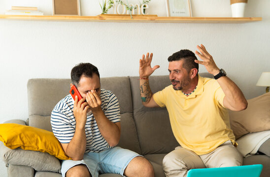 Men arguing at home while one is on a phone call