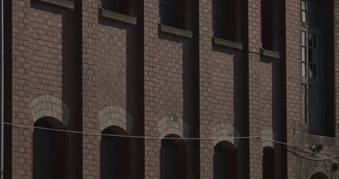 Red brick industrial building facade tall arched windows and glass in sunlight