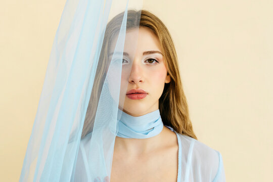 Woman with sheer blue fabric covering face