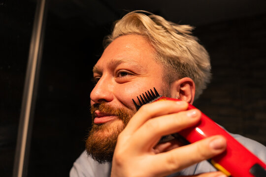 Man Grooming Beard With Electric Trimmer