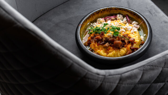 Traditional Ukrainian Banosh with Pork Cracklings and Bryndza Presented on Gray Upholstered Chair