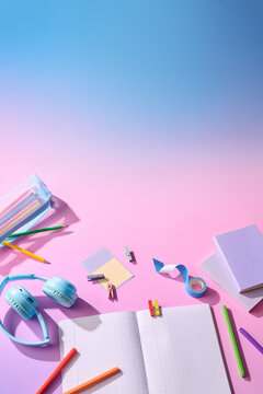 Back to school supplies arranged on a gradient pink and blue