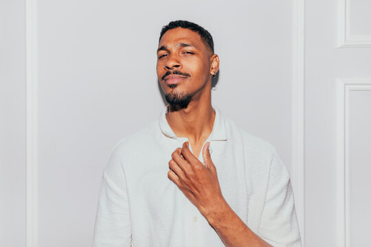 Confident man in white shirt posing indoors in daylight