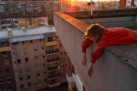 Young Woman Resting Over Rooftop Edge At Sunset