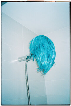 a wet blue wig hangs from a shower head, 35mm film