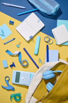 School supplies neatly arranged on a yellow and blue background,