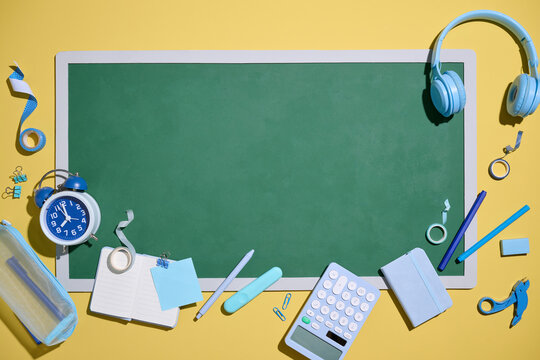 School supplies arranged around a green chalkboard