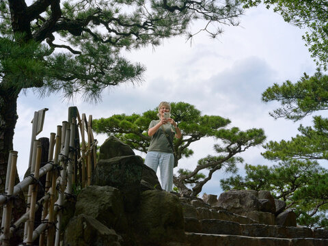 Tourist  Takes a Picture on a Stone Path at a Garden