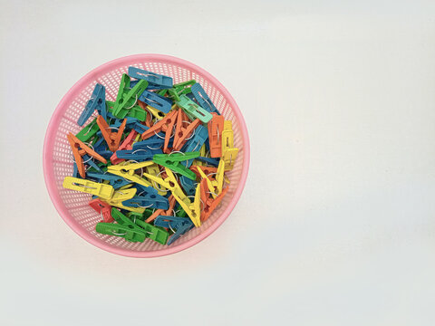 A basket full of clothes pins isolated on the white background, multi color plastic laundry clips or clothes pegs