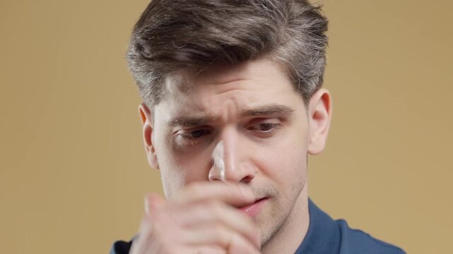 Worried man biting his lips with restless eyes in a studio portrait. Yellow background. Anxiety, anticipation, panic, insecurity and emotional pressure.