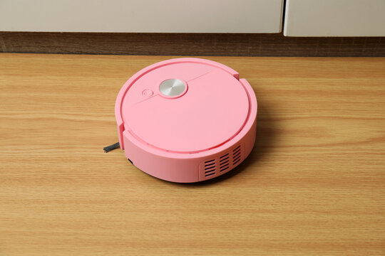 Robotic vacuum cleaner on laminate floor in living room. Smart cleaning technology.