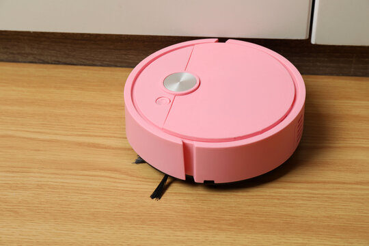 Robotic vacuum cleaner on laminate floor in living room. Smart cleaning technology.