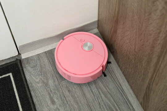 Robotic vacuum cleaner on laminate floor in living room. Smart cleaning technology.