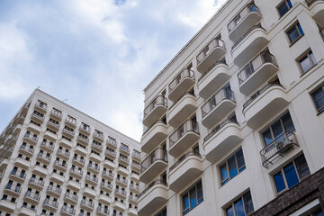 Fototapeta premium Close-up view of modern apartment buildings with curved balconies and dramatic cloudy sky.