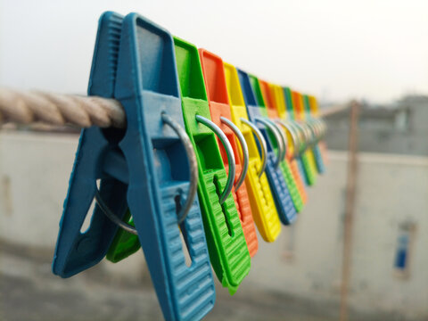 Set of multicolor plastic clothes pins or clothes pegs for house hanging on rope on roof top, laundry clips set, close up