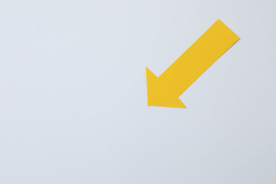 Paper arrow on color background, top view