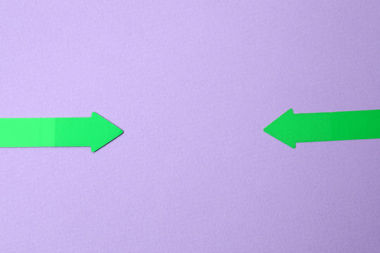Paper arrow on color background, top view
